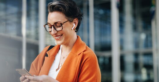 Smiling businesswoman reading a text message on her phone while commuting to her office in the city