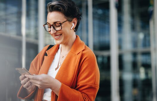 Smiling businesswoman reading a text message on her phone while commuting to her office in the city