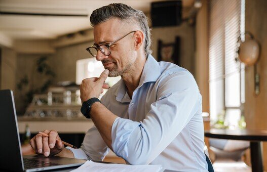 European grey man working with papers and laptop at office