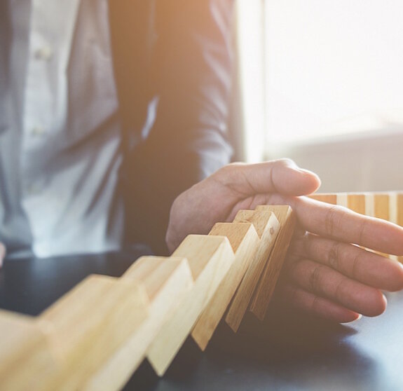 Problem Solving,Close up view on hand of business woman stopping falling blocks on table for concept about taking responsibility.