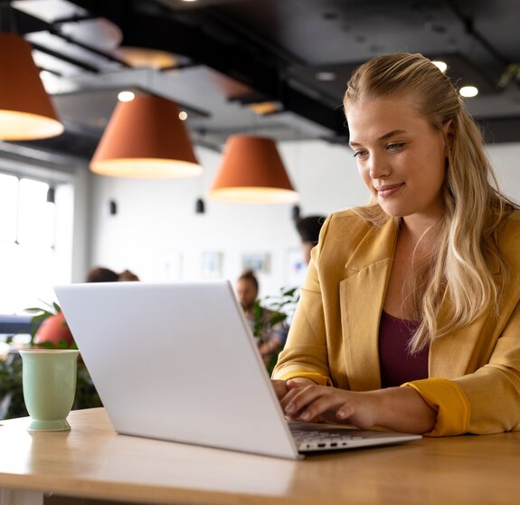 Happy caucasian casual businesswoman using laptop at desk