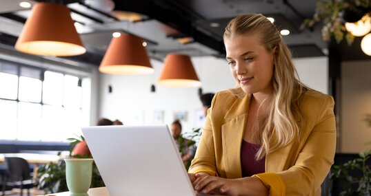 Happy caucasian casual businesswoman using laptop at desk