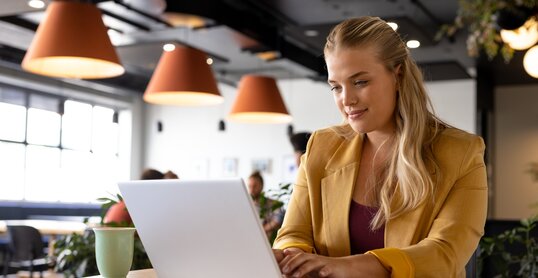 Happy caucasian casual businesswoman using laptop at desk