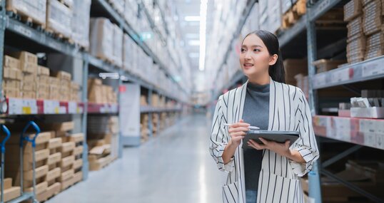 Portrait of asian woman business owner using digital tablet checking amount of stock product inventory on shelf at distribution warehouse factory