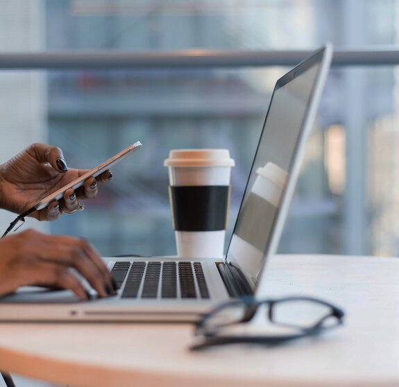 Frau arbeitet remote mit Smartphone und Laptop