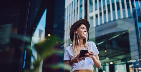 Cheerful woman listening to music in cafe