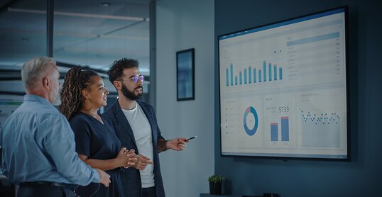 Company Operations Manager Holds Meeting Presentation. Diverse Team Uses TV Screen with Growth Analysis, Charts, Statistics and Data. People Work in Business Office.