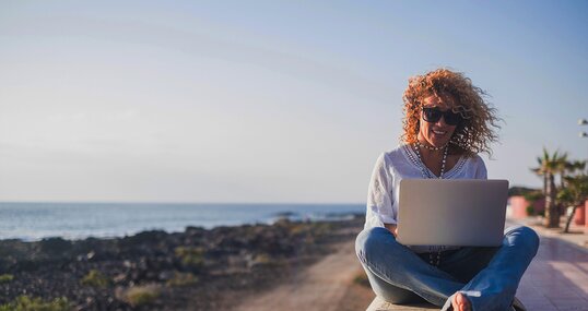 Happy lifestyle digital nomad young cheerful woman work outdoor with laptop computer - people and modern technology job and communication related - alternative office at the beach