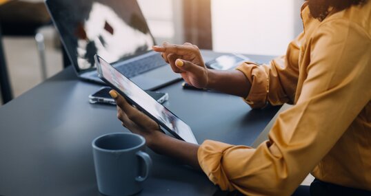 Portrait of Young Asian woman hand freelancer is working her job on computer tablet in modern office. Doing accounting analysis report real estate investment data, Financial and tax systems concept.