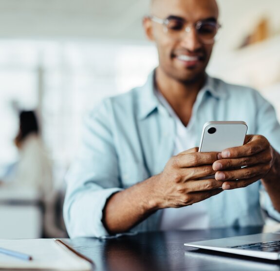 Business man sitting in an office and using a smartphone