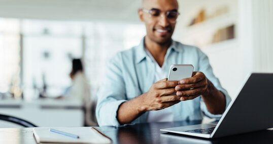 Business man sitting in an office and using a smartphone