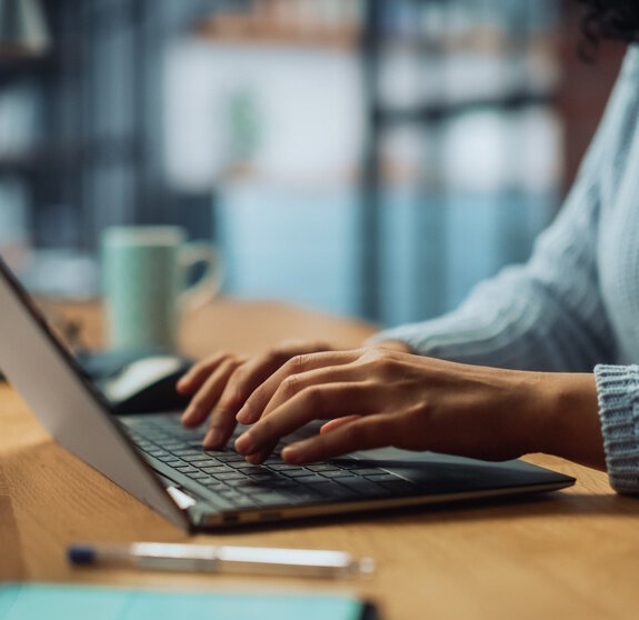 Close Up on Hands of a Female Specialist Working on Laptop Computer at Cozy Home Living Room while Sitting at a Table. Freelancer Woman Chatting Over the Internet on Social Networks.