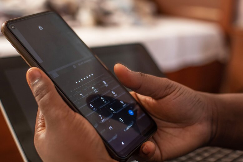 hands only of a woman opening her locked phone, entering the pin