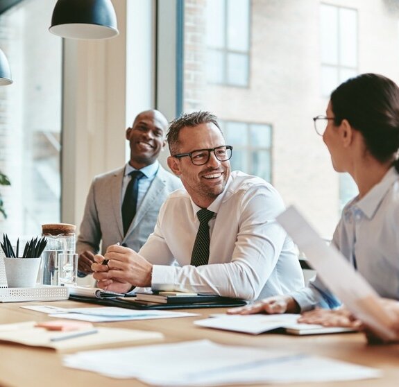 Diverse businesspeople laughing during a meeting around an offic