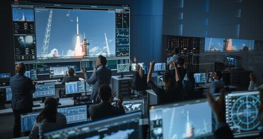 Group of People in Mission Control Center Witness Successful Space Rocket Launch. Flight Control Employees Sit in Front Computer Displays and Monitor the Crewed Mission.