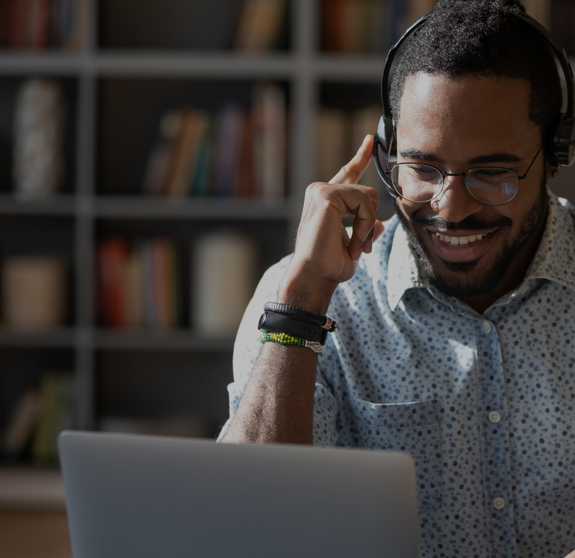 Focused African man sitting at desk wear headset watching webinar video course gain new knowledge use on-line application website. Manager talk to client provide professional help and support concept