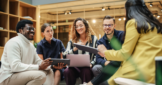 Multiethnic Group of People Meeting and Discussing Innovative Ideas in a Casual Conference Room in the Office. Smiling Colleagues Putting Together a Presentation