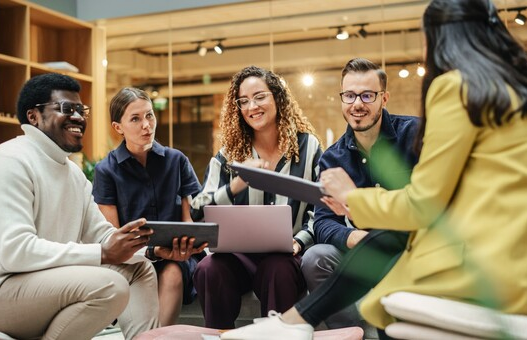 Multiethnic Group of People Meeting and Discussing Innovative Ideas in a Casual Conference Room in the Office. Smiling Colleagues Putting Together a Presentation