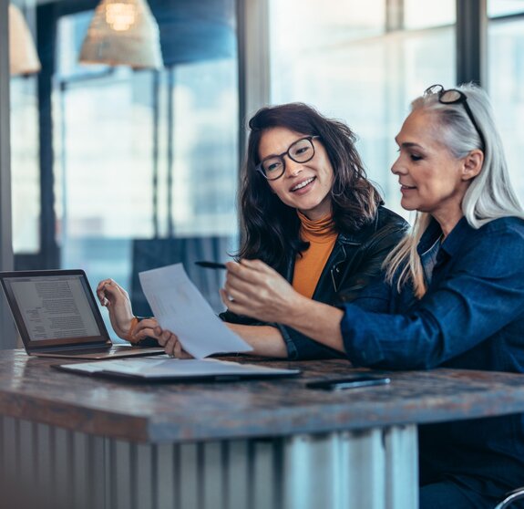 Two women analyzing documents at office