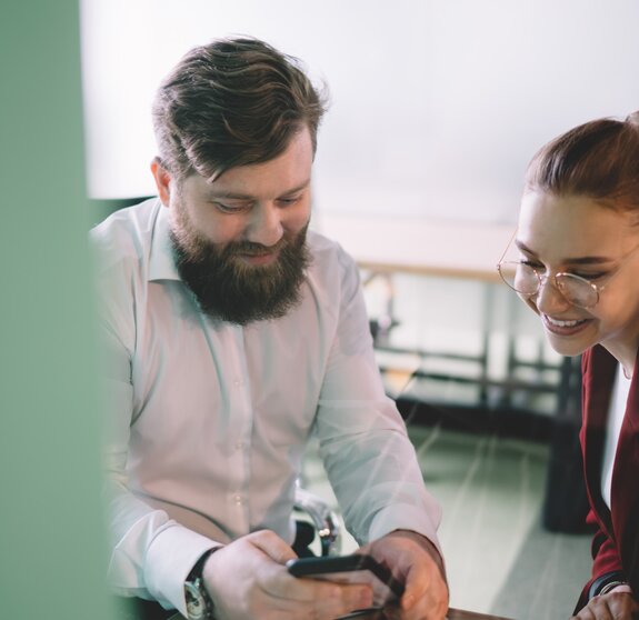 Work partners sitting in office surfing phone in company