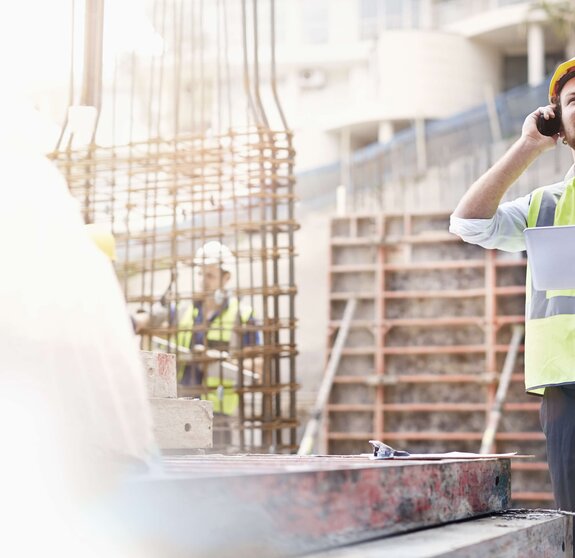 Ingenieur mit einem Tablet in der Hand telefoniert auf einer Baustelle