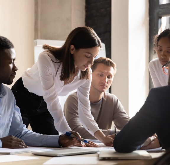 Diverse colleagues working on project together, sitting at table in boardroom, working with legal documents, financial report with statistics, employees engaged in teamwork at corporate meeting