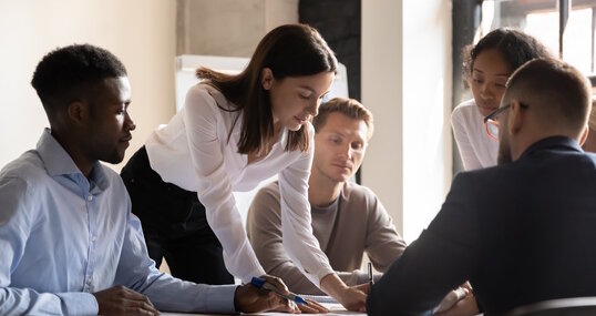 Diverse colleagues working on project together, sitting at table in boardroom, working with legal documents, financial report with statistics, employees engaged in teamwork at corporate meeting