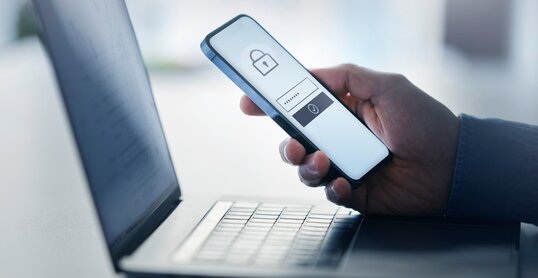 Man holding smart phone with data security on display at office