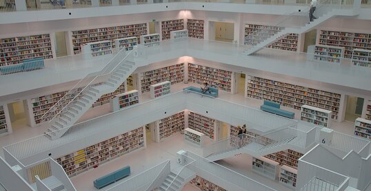 Ein Gang mit deckenhohen Regalen zu beiden Seiten, in denen ungeordnet Bücher gestapelt sind.